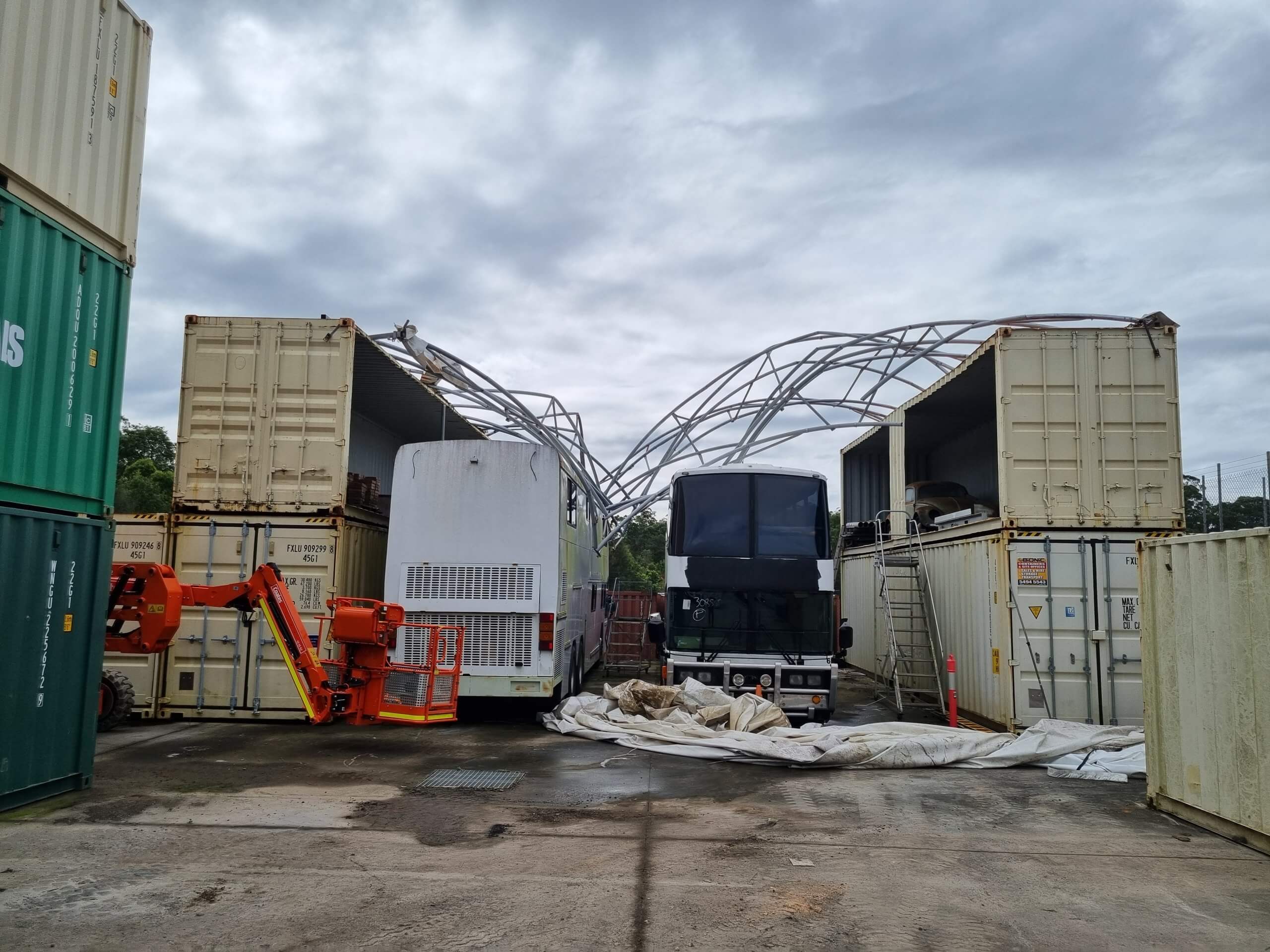 Chinese made fabric dome shelter collapsed and storm damaged. It has collapsed over two buses and sits between 2 x sets of double stacked shipping containers in a shipping container yard